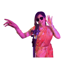 a woman wearing sunglasses and a red sari is dancing in front of a microphone