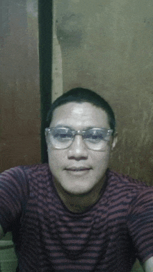 a man wearing glasses and a striped shirt is smiling