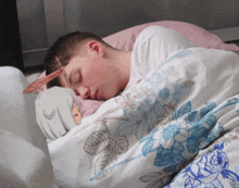 a man is sleeping on a bed with a blue and white blanket