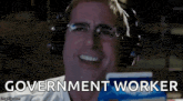 a man wearing headphones and glasses is smiling and holding a book with the words government worker written on it .