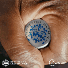 a person holding a bottle cap that says brewed extra cold at 25 degrees