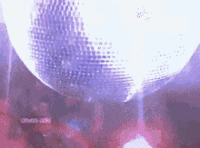 a disco ball is spinning in a dark room with people dancing in the background .
