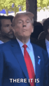 a man in a suit and tie is standing in front of a crowd and says `` there it is '' .