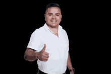 a man wearing a white shirt is giving a thumbs up