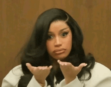 a woman with long black hair is making a funny face with her hands in the air .