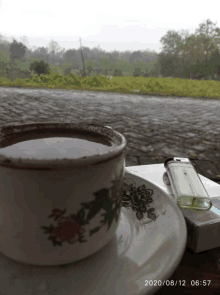 a cup of coffee is on a saucer next to a pack of cigarettes and a lighter