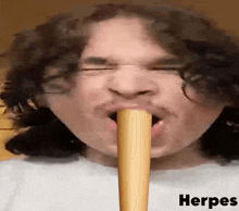 a man with curly hair is holding a wooden bat in his mouth with the word herpes written below him