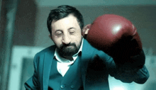 a man in a suit is wearing boxing gloves and making a funny face .