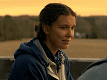 a woman wearing a blue hoodie and a bandana looks down