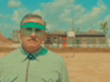 a man wearing green sunglasses and a green shirt is standing in a field .