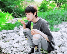 a young man is blowing bubbles while kneeling on rocks .