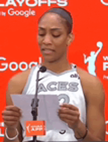 a female basketball player is giving a speech in front of a microphone .