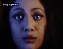 a close up of a woman 's face with a surprised look on her face in a dark room .