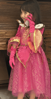 a little girl dressed in a pink dress and pink gloves