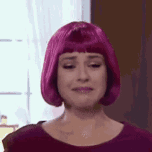 a woman wearing a pink wig is crying and making a sad face .