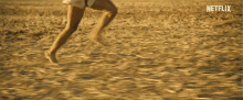 a woman in a white dress is running in a field with mountains in the background and a netflix logo in the corner