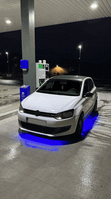 a white car is parked at a gas station with blue lights