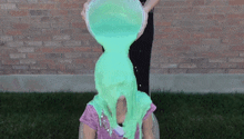 a person pouring green slime on another person 's face