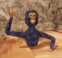 a blue monkey with a hood on stands on a wooden surface