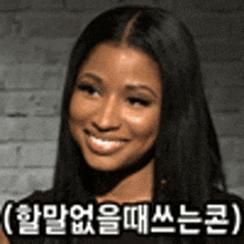 a woman with long black hair is smiling in front of a brick wall with korean writing .