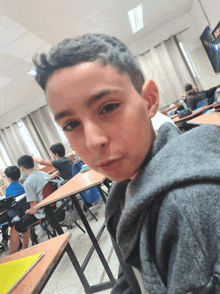 a boy sitting at a desk in a classroom with other kids