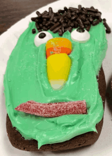 a cookie with green frosting and candy corn on it looks like a monster