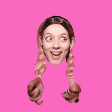 a woman with pigtails on a pink background making a funny face