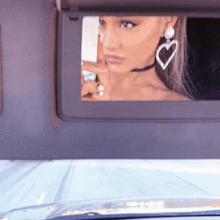 a woman is taking a picture of herself in a car sun visor .