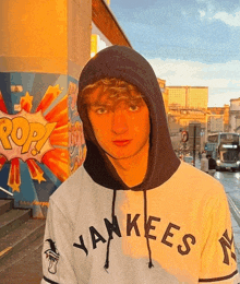 a man wearing a yankees hoodie is standing in front of a pop art mural