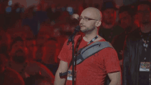 a bald man singing into a microphone with a lanyard around his neck that says ' sd ' on it