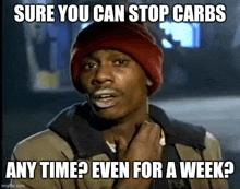 a man wearing a red hat and a jacket is making a funny face and asking if he can stop carbs any time .