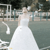 a woman in a wedding dress is standing on a field with a roll of toilet paper in front of her