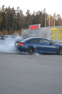 a blue car is doing a burnout in front of a building that says flatragen