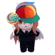 a stuffed doll wearing a rainbow hat and holding a colorful lollipop