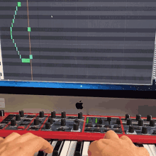 a person is playing a red keyboard in front of an apple computer