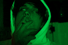 a man smoking a cigarette with a green background