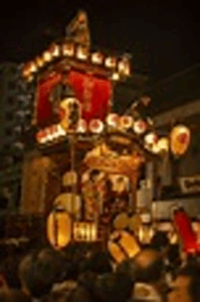 a group of people are standing in front of a building with lanterns on it at night .