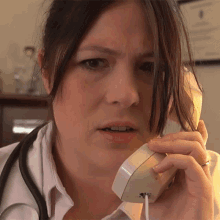 a woman with a stethoscope is talking on a phone