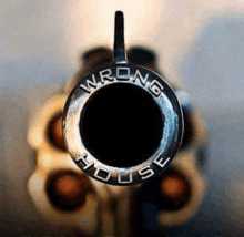 a close up of the barrel of a revolver with a ring that says wrong house on it .