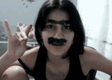 a woman with a fake mustache on her face is giving a peace sign