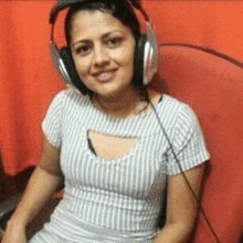 a woman wearing headphones is sitting in a chair and smiling .