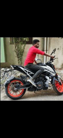 a young man in a red shirt sits on a motorcycle