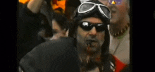 a man wearing sunglasses and a helmet with blood on his face .