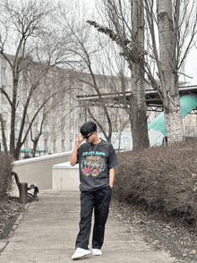 a man wearing a black t-shirt with a tiger on it walking down a path