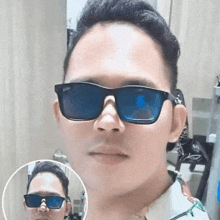 a man wearing sunglasses looks at himself in the mirror .