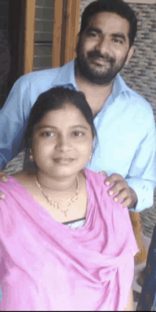 a man and a woman are posing for a picture and the woman is wearing a necklace