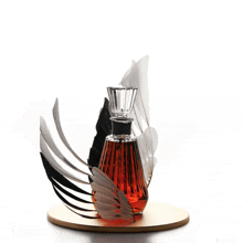 a perfume bottle with feathers around it on a table