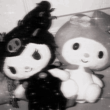 two stuffed animals , one black and one white , are sitting next to each other .