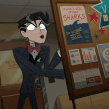 a man in a suit is standing in front of a bulletin board with a poster that says a whole week of just sharks