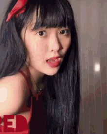 a girl with long black hair is wearing a red dress and a red bow in her hair